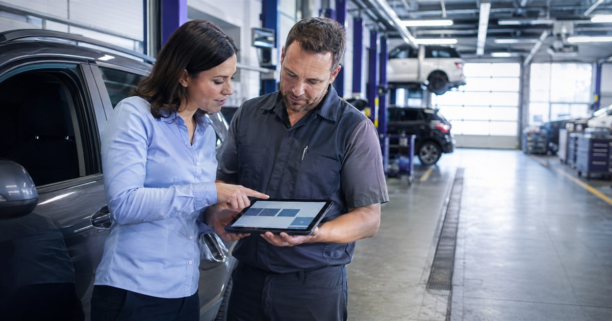 Dealership service advisor and technician reviewing a vehicle inspection workflow on a tablet in a service bay